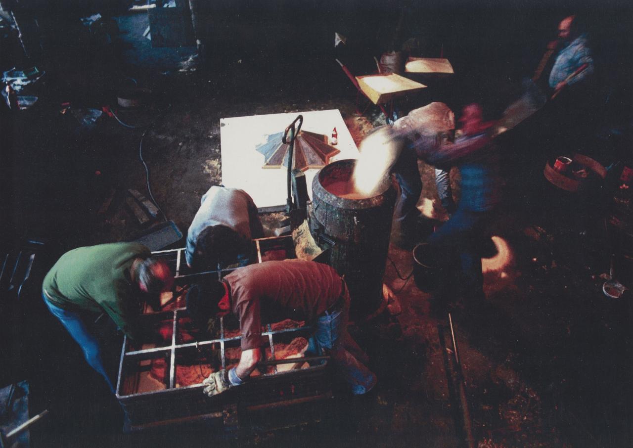 Das Foto aus den Jahren 1980-1982 zeigt drei Männer, die sich über eine großen Kiste beugen.