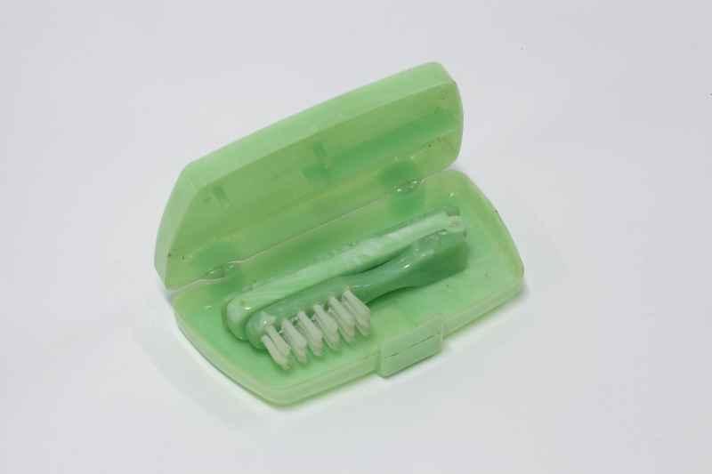 Das Foto zeigt einen aufgeklappten grünen Zahnbürstenbehälter mit Zahnbürste