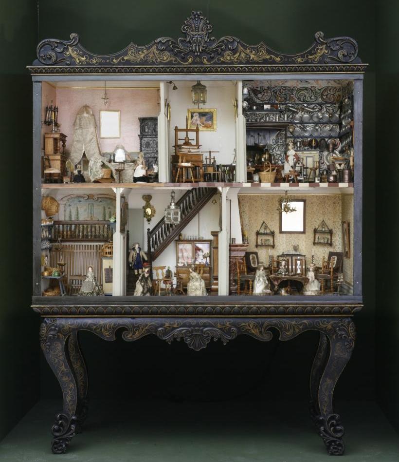 Das Foto zeigt ein historisches Puppenhaus mit zwei Etagen mit jeweils drei Zimmern, die unterschiedlich eingerichtet sind.