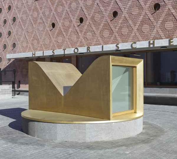 Das Foto zeigt die M-förmige Skulptur auf dem Museumsvorplatz. 